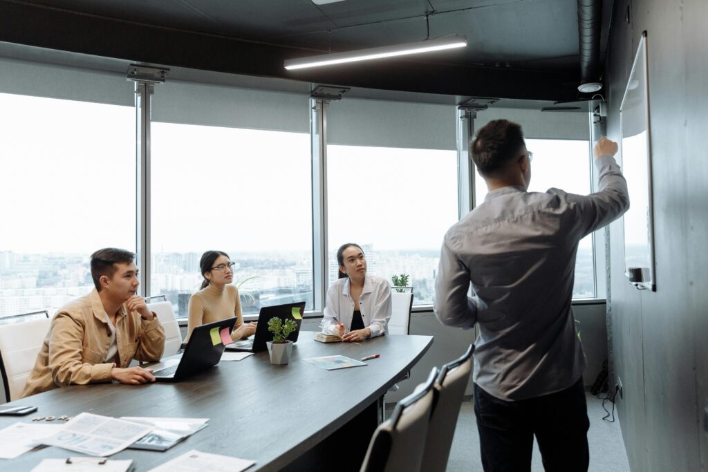 pexels-photo-7654000-7654000 Colleagues in a meeting room discussing a presentation with city views.